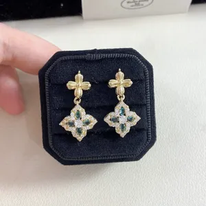Close-up detail of vintage style gold earrings with green and white crystal clover drops