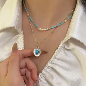 Close-up of layered pearl and turquoise bead necklace worn with white blouse