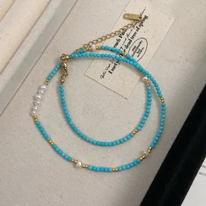 Close-up of natural turquoise stone and freshwater pearl beaded necklace on a linen tray