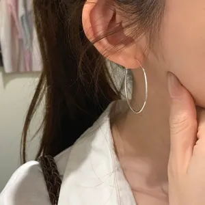 Primo piano di eleganti orecchini a cerchio in argento minimalisti su un orecchio.