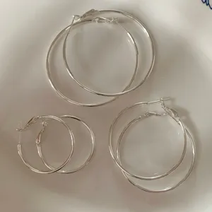 Foto macro di tre paia di orecchini a cerchio sottili minimalisti in argento di diverse dimensioni