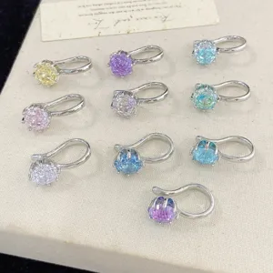 A collection of assorted colorful crystal clip-on ear cuffs on a cream display
