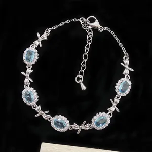 Bracelet élégant plaqué argent avec zircons ovales bleu clair et breloques en forme de nœud