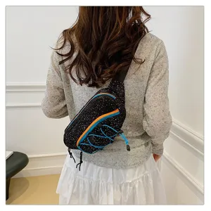 Back view of a woman wearing a sporty black speckled chest bag with blue bungee details.