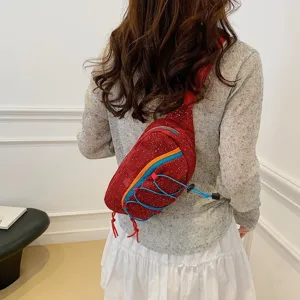 Trendy red corduroy chest bag with blue bungee cord accents and sports style design