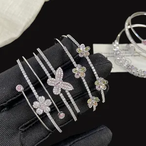 Vista dettagliata di un bracciale multistrato scintillante con fiori e farfalle.