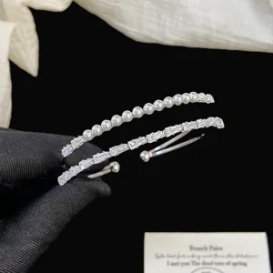 Vista dettagliata di un elegante bracciale rigido argentato con perle e cristalli.