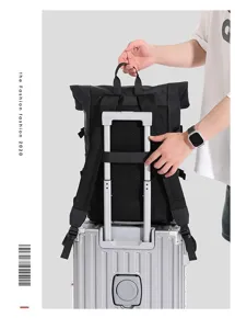 Detail of black roll-top backpack mounted on silver luggage handle.