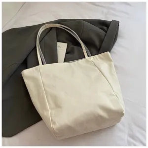 Nahaufnahme der cremefarbenen Canvas-Tasche, die Textur und Design zeigt.