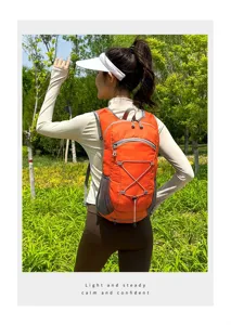 Orange lightweight hiking backpack shown on model in sunny outdoor park setting