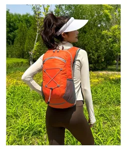 Rear view of an orange lightweight outdoor cycling backpack worn by a model in nature