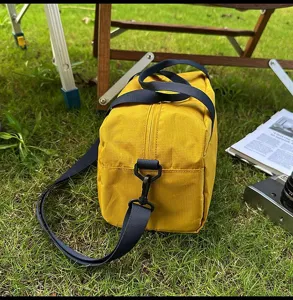 Detailansicht der gelben Nylon-Sporttasche mit blauem Gurt beim Outdoor-Camping