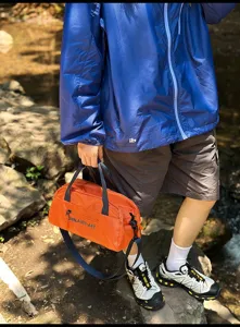 Detailansicht der leuchtend orangefarbenen leichten Sport-Umhängetasche für draußen.