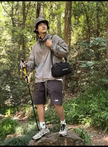 Schwarze sportliche Umhängetasche in einer Wald-Wander-Szene mit einem asiatischen Modell