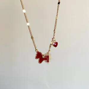 Detailed macro view of a gold chain necklace with red enamel horse and heart charms