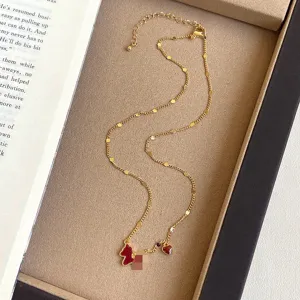 Detail shot of a vintage gold chain necklace featuring a red horse and heart charm.