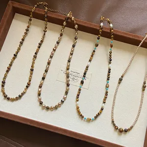 Collection of four natural tiger eye and pearl beaded necklaces in a brown tray