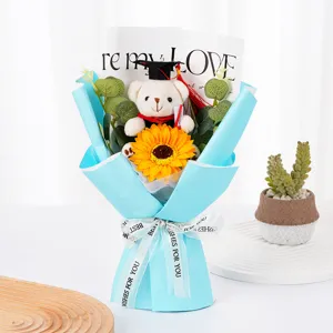 Bouquet de fleurs tournesol ours de remise des diplômes avec papier bleu et ruban cadeau.