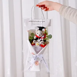 Vista detallada de ramo de flores tejidas a mano con oso de graduación en bolsa de regalo