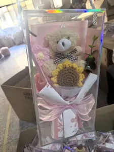 Detailed view of handmade crochet sunflower bear bouquet in transparent gift box for graduation.