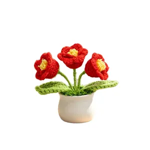 Fleurs rouges tricotées à la main en pot avec vase blanc pour déco de bureau.