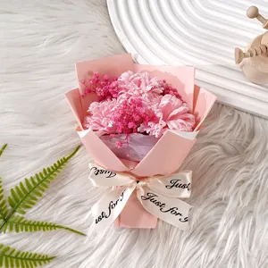 Rosa künstlicher Blumenstrauß verpackt mit getrocknetem Schleierkraut als Geschenk.