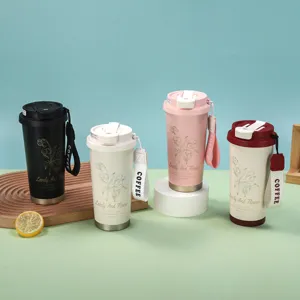 Vue détaillée des tasses à café isothermes en acier inoxydable avec motif floral et lanière.