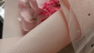 Close-up detail of pink bouquet wrapping mesh and delicate texture for romantic gift packaging.