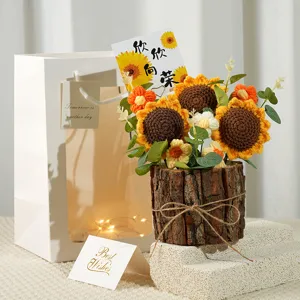 Detailed view of handmade knitted sunflower bouquet with gift bag and wooden pot for decoration.