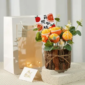 Detailed view of handmade crochet orange potted flower in rustic wooden pot with gift bag.