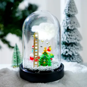 Vue de détail de la boule de neige en verre de Noël lumineuse avec mini sapin et décor.