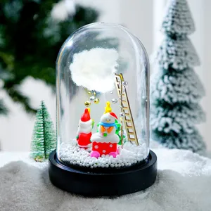 Gros plan détaillé de la boule de neige lumineuse de Noël avec un mini paysage hivernal.