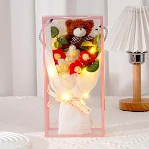 Nahaufnahme eines handgestrickten Bärenstraußes in Geschenkbox mit warmem LED-Licht