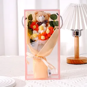 Detail von handgestrickten Blumen und einem süßen Teddybär in einer rosa Geschenkbox