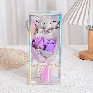 Nahaufnahme von lila Seifenrosen und Teddybär in einer transparenten Geschenkbox