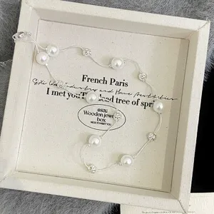 Detail view of a dainty pearl and silver bead necklace on a canvas jewelry tray