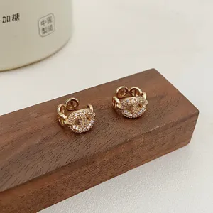 Detailed macro view of gold-toned pavé pig nose ear cuffs on a dark wooden block