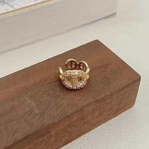 Close-up of sparkling gold pavé-set pig nose ear cuff on a wooden base