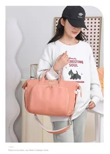 Modella asiatica con una grande borsa per pannolini rosa pesca in un ambiente moderno