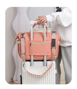 Borsa fasciatoio rosa salmone con fascia per bagagli fissata su una valigia bianca