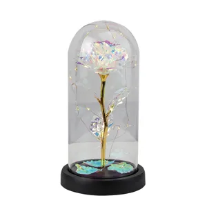 Rose en feuille d'or irisée dans un dôme en verre avec guirlande lumineuse LED noire