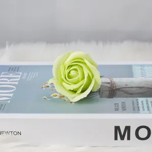 Hellgrüner Seifenrosenkopf auf dekorativem Buch für DIY-Blumensträuße und Valentinstag
