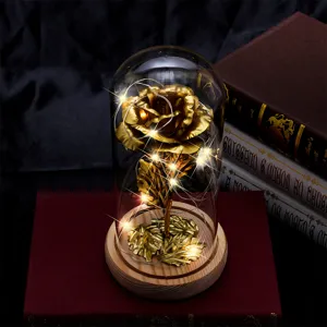 Detailed macro view of a gold foil eternal rose in a glass dome with warm LED lights