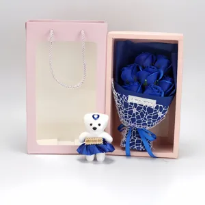 Detailed view of 7 blue soap roses bouquet with a small teddy bear in a pink gift box.