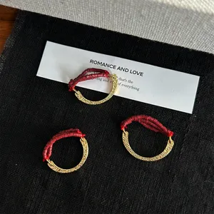 Close-up of C-shaped hammered metal rings with elastic red seed bead bands