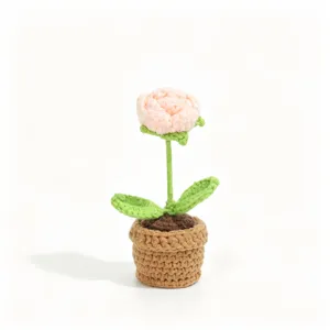 Close-up detail of a handmade crochet potted flower, exquisite pink bloom and green leaves.