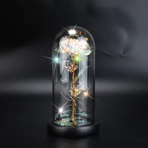 Nahaufnahme einer schillernden goldfarbenen Rose mit LED-Lichtern in einer Glaskuppel