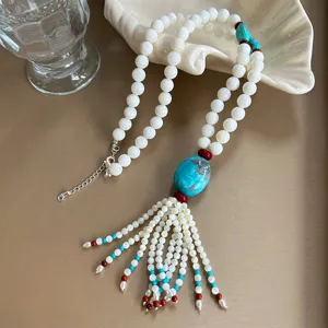 Close-up of vintage Tibetan style long necklace with white beads and turquoise tassel