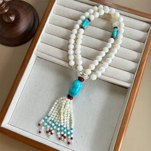 Detailed view of Tibetan style beaded necklace featuring turquoise pendant and tassel.