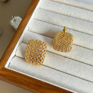 Primer plano de elegantes pendientes de botón cuadrados dorados con textura de malla